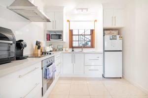 a kitchen with white cabinets and a refrigerator at Magnolia on Colville - Historic Riverside Elegance in Hobart