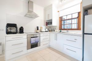 a kitchen with white cabinets and a stove top oven at Magnolia on Colville - Historic Riverside Elegance in Hobart