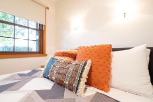 a bedroom with a bed with pillows and a window at Magnolia on Colville - Historic Riverside Elegance in Hobart