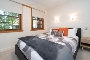 a bedroom with a bed and two windows at Magnolia on Colville - Historic Riverside Elegance in Hobart