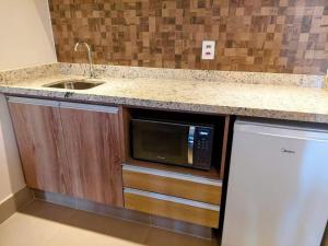 eine Küche mit Spüle und Mikrowelle in der Unterkunft Solar das Águas Park Resort, Ap para Temporada in Olímpia