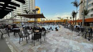 eine Terrasse mit Tischen und Stühlen sowie einem Pool in der Unterkunft Solar das Águas Park Resort, Ap para Temporada in Olímpia