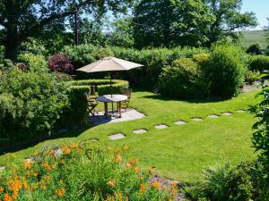 a table with an umbrella in a garden at The Smithy in Brentor