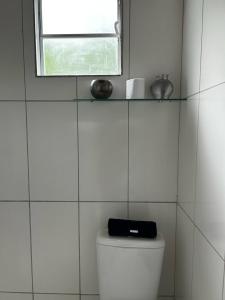 Un baño con azulejos blancos y una ventana encima del inodoro. en Peaceful Retreat in Atlantic Forest, en Recife