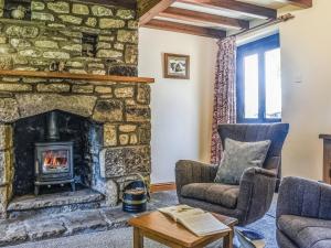 a living room with a stone fireplace and two chairs at Ladycroft Cottage in Hebden