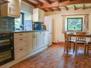 a kitchen with white cabinets and a table with chairs at Ladycroft Cottage in Hebden +15 photos