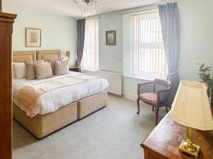 a bedroom with a bed and a chair and windows at St Anne's Cottage in Torquay