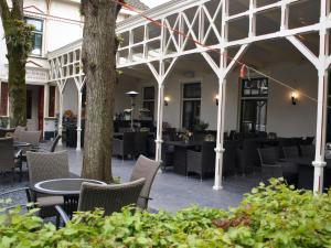 een patio met tafels en stoelen en een boom bij Hotel-Restaurant Het Rechthuis in Muiderberg