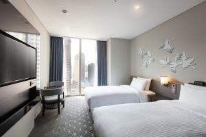 a hotel room with two beds and a flat screen tv at Hotel Gracery Seoul in Seoul