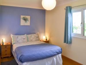 a bedroom with a bed with blue sheets and a window at Treyarnon in St Merryn