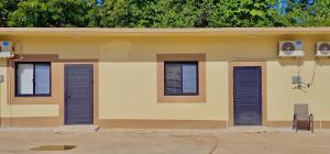 a house with three windows and blue shutters on it at Pedros Heights 2 Bedroom & 1 Bathroom in Tumon