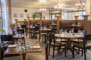 a restaurant with wooden tables and chairs and windows at Holiday Inn York by IHG in York