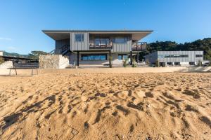a house on the beach with a sandy beach at Kaiteriteri Reserve Cabins in Kaiteriteri