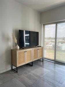 - un salon avec une télévision à écran plat sur une armoire en bois dans l'établissement Acogedor departamento en solares zona real, alberca, gym y terrazas, à Guadalajara