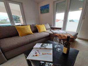 ein Wohnzimmer mit einer Couch und einem Tisch mit einer Flasche Wein in der Unterkunft Beachfront Apartment with Balcony and Sea View in Vrsi