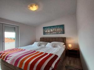 ein Schlafzimmer mit einem Bett mit einer gestreiften Decke in der Unterkunft Beachfront Apartment with Balcony and Sea View in Vrsi