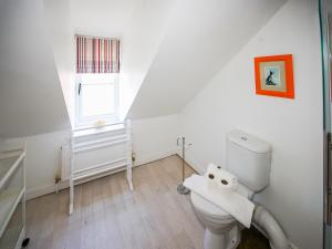a white bathroom with a toilet and a window at Wherry Cottage in Wells next the Sea