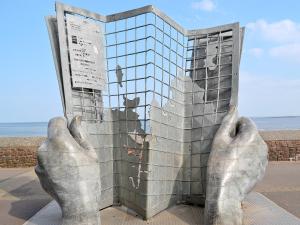 une statue de deux mains tenant une fenêtre dans l'établissement Dove Cottage, à Minehead 2 autres photos