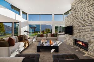 ein Wohnzimmer mit einem großen Steinkamin in der Unterkunft Oraka Lakeside Retreat by Sotheby's Luxury Rental Homes in Queenstown Airport