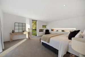 ein weißes Schlafzimmer mit einem großen Bett und einem Kamin in der Unterkunft Oraka Lakeside Retreat by Sotheby's Luxury Rental Homes in Queenstown Airport + 11 Fotos