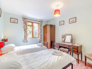 a bedroom with two beds and a desk and a mirror at Bryanstown Annexe in Woodbridge