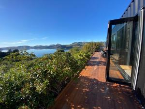 a house with a balcony with a view of a lake at Weka St Eco Cabin in Dunedin