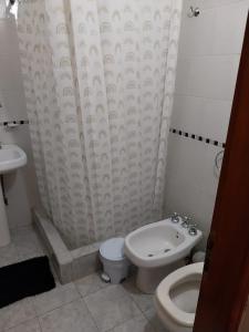 a bathroom with a toilet and a shower curtain at LoDeLira Apart in Federación