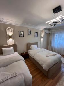 two beds in a hotel room with white sheets at Zamalek by the nile 3BR in Cairo