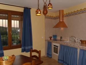 a kitchen with a table and a blue curtain at Casa Rural Del Antiguo Hojalatero in Ibdes