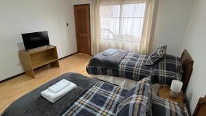 a bedroom with two beds and a television in it at Hotel Glaciares de Atacama in Copiapó
