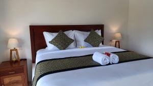 a bedroom with a large bed with towels on it at Santika villa ubud in Ubud
