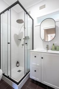 Un baño blanco con ducha y lavabo. en Kiama Country Oasis, en Kiama