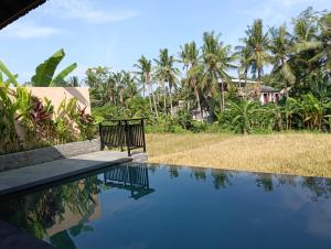 a swimming pool in front of a house with palm trees at Santika villa ubud in Ubud