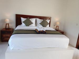 a bedroom with a large white bed with two flip flops at Santika villa ubud in Ubud +3 photos