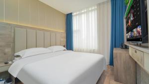 a bedroom with a white bed and a flat screen tv at 景莱酒店上海南京东路店 in Shanghai