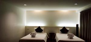 2 Betten in einem Zimmer mit Wandbeleuchtung in der Unterkunft De Poem Loft Boutique Residence in Hat Yai