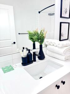 un lavandino bianco del bagno con vasi e asciugamani neri di Cozy 2 BR Suite Self check-in I Free Park Pass a YYC