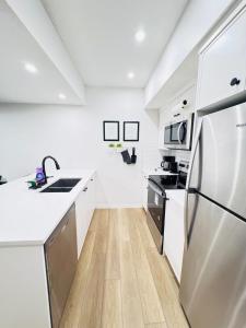 una cucina con banconi bianchi e frigorifero in acciaio inossidabile di Cozy 2 BR Suite Self check-in I Free Park Pass a YYC Altre 16 foto