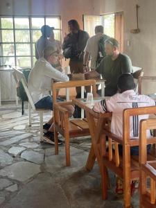 un groupe de personnes assises autour d'une table dans l'établissement AMENITY TOURs & CAMPING - SERENGETI, à Lukungu