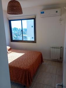 a bedroom with a bed and a large window at Departamento en el corazón de Villa Carlos Paz in Villa Carlos Paz