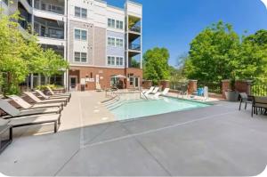 a swimming pool with lounge chairs and a building at Uptown Charlotte Modern Stay 2BR in Charlotte