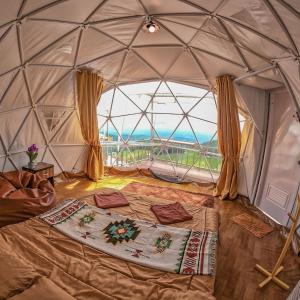 a room with a bed in a dome with a large window at Phu Boek Fah Camping in Mon Jam