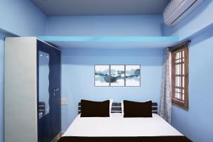 a bedroom with blue walls and a bed with black pillows at Hotel O Happy Hotel in Raipur +21 photos
