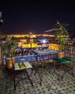 una mesa y sillas en un balcón por la noche en Dar El Mathaf, en Fez
