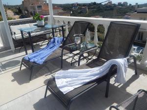 trzy krzesła i stół na balkonie ze stołem w obiekcie Peggy's Villa-House with private pool 25' from Athens Intl Airport w mieście Drafí