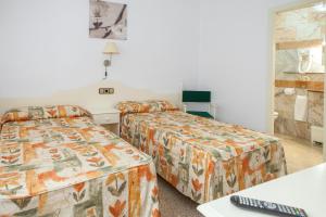 Una habitación de hotel con dos camas y un teclado. en Hotel Agora, en Port de la Selva