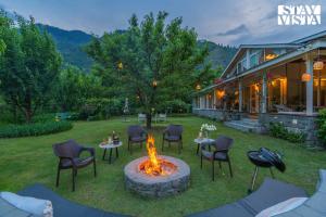 a fire pit in a yard next to a house at StayVista at Mayflower Aramgarh with Orchards, BBQ in Manāli
