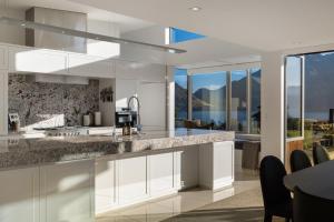 eine Küche mit weißen Schränken und Granitarbeitsflächen in der Unterkunft Oraka Lakeside Retreat by Sotheby's Luxury Rental Homes in Queenstown Airport