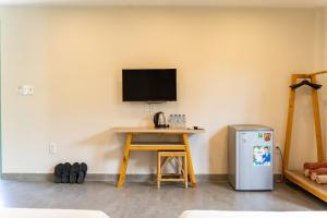a room with a desk and a television on a wall at Meraki Oasis Hotel in Mui Ne
