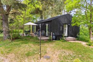 a black shed with a porch and an umbrella at New House Near Asserbo Plantation And Arresø in Frederiksværk